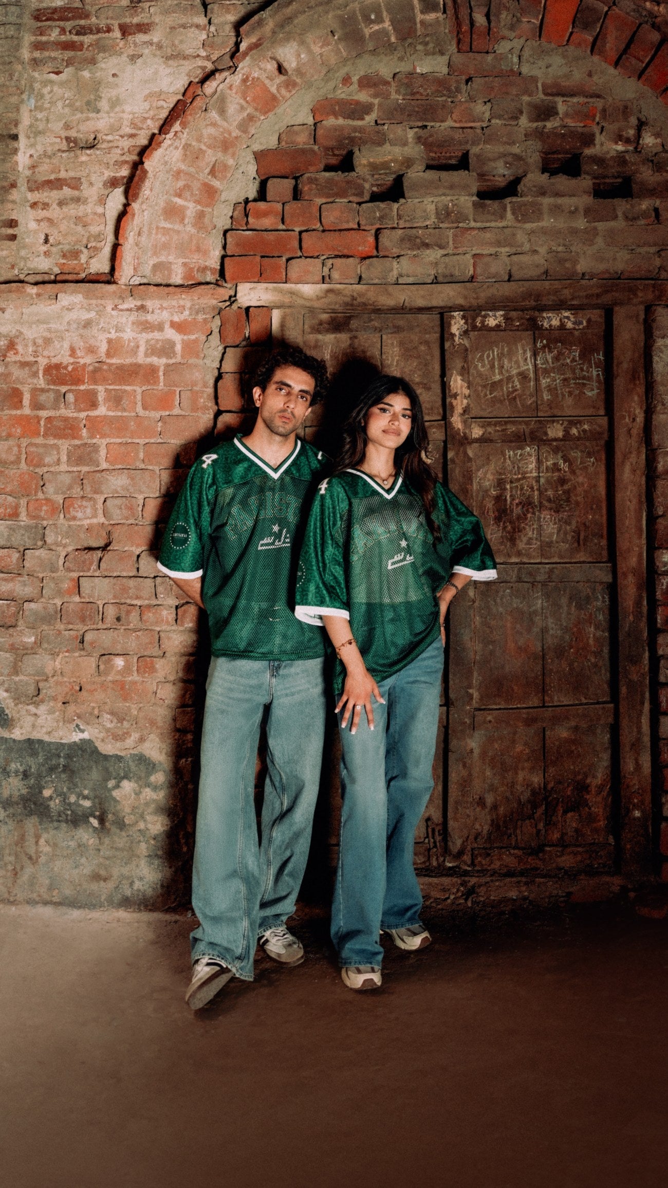 Zamana Athletic Department campaign — two models in green jerseys beside a brick archway in Lahore